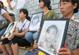 地震で犠牲になった子どもたちの遺影を掲げ、四川省都江堰市の裁判所前に集まった親たち=3日(共同)