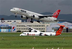 8月12日、韓国の釜山国際空港で滑走路から緑地帯に飛び出したボンバルディア機(下)(AP)<br />